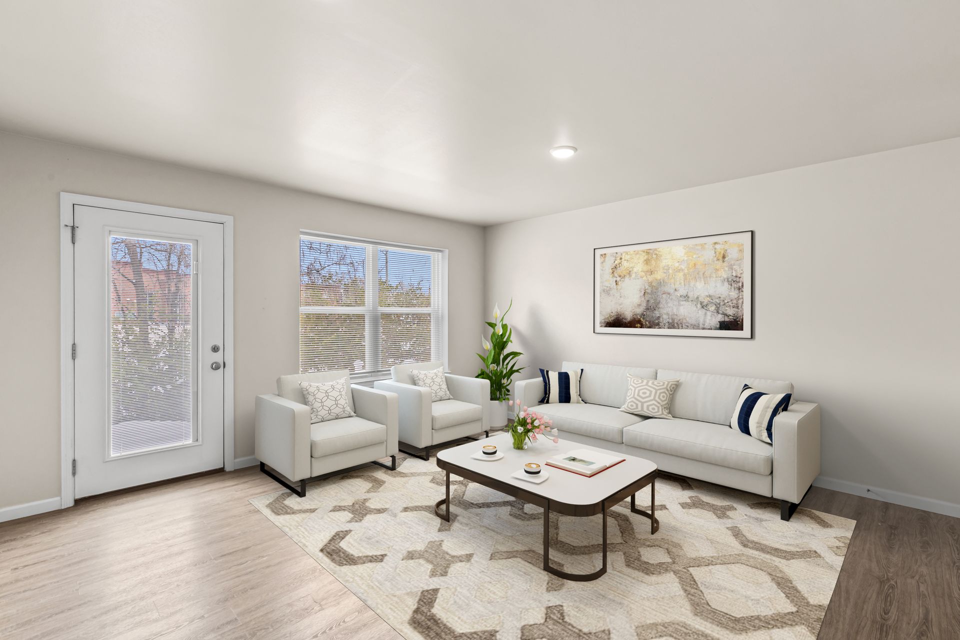 Bright modern living room with white sofa, armchair, coffee table, rug, and wall art