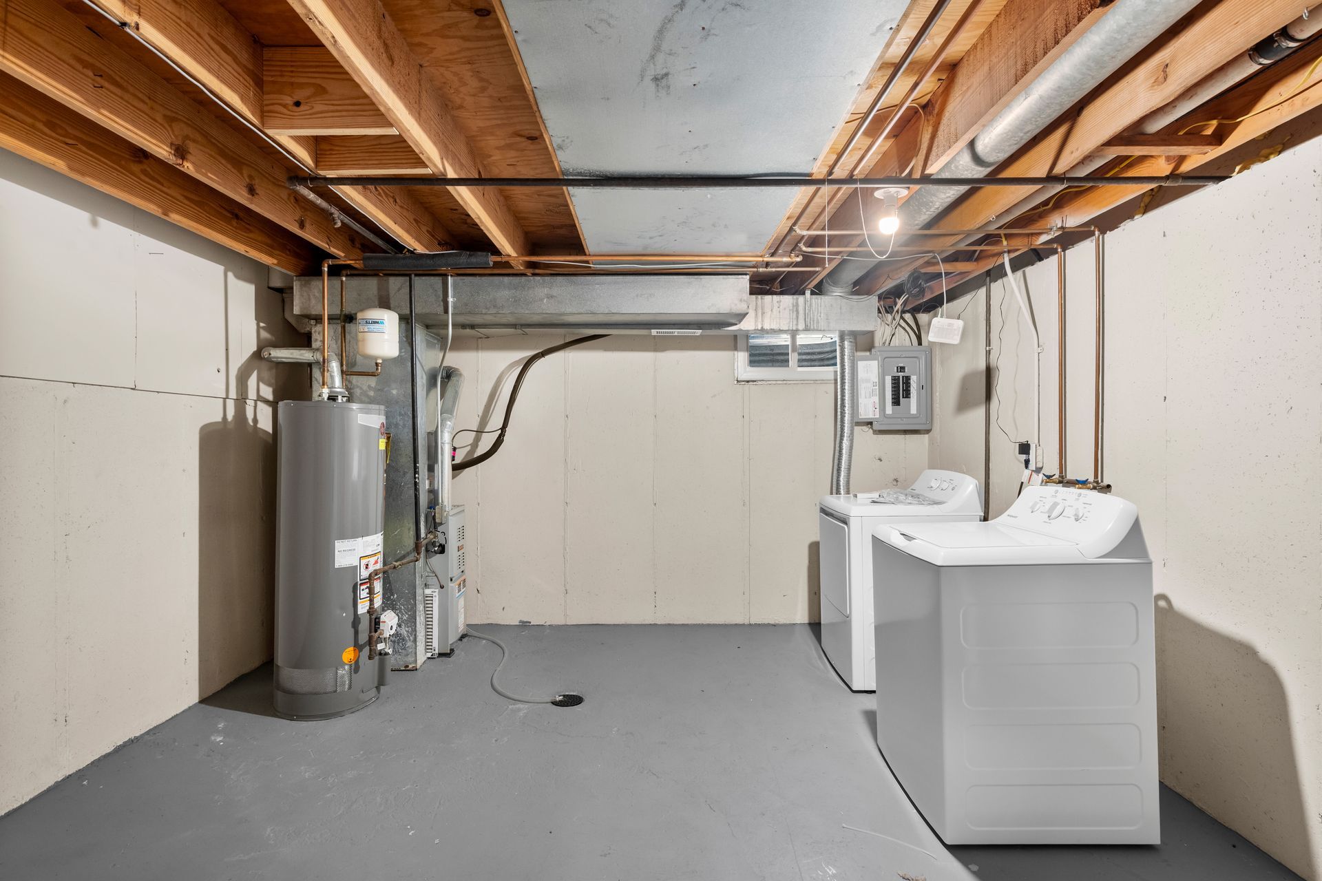 Basement laundry area with water heater, utility sink, and exposed ceiling joists