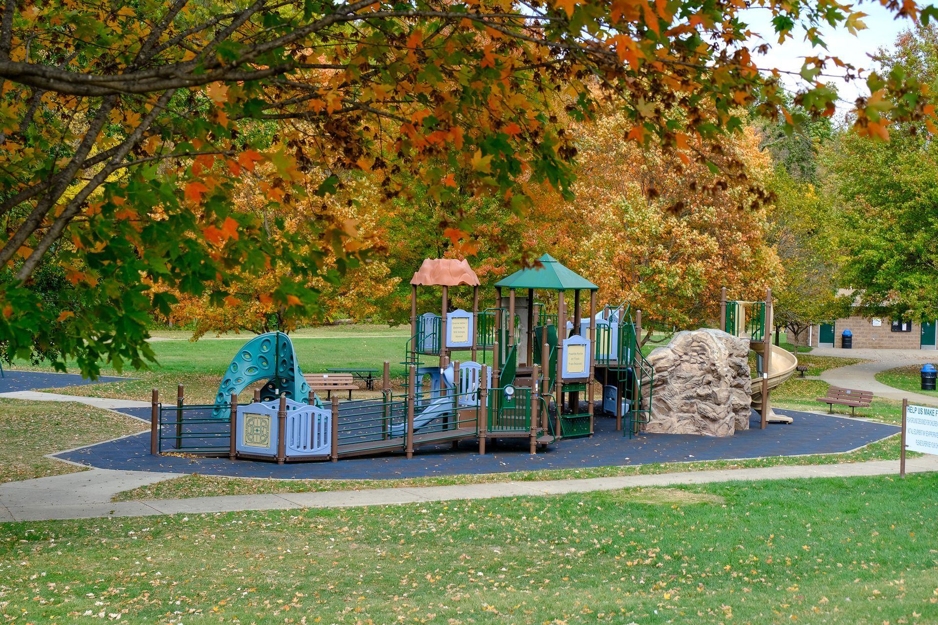 Playground with colorful play structures under autumn trees in a park