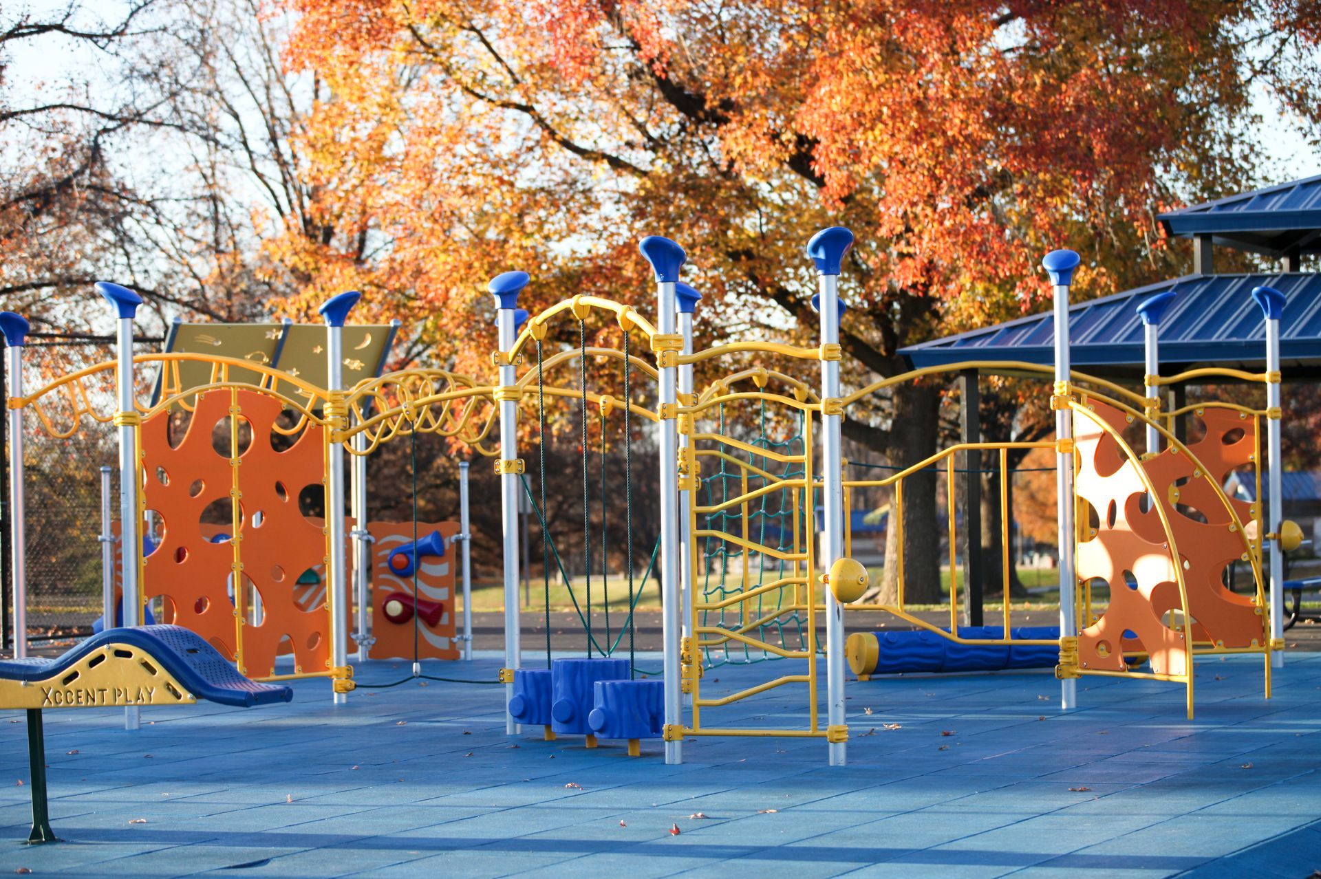 Colorful playground with climbing structures and slides under autumn trees