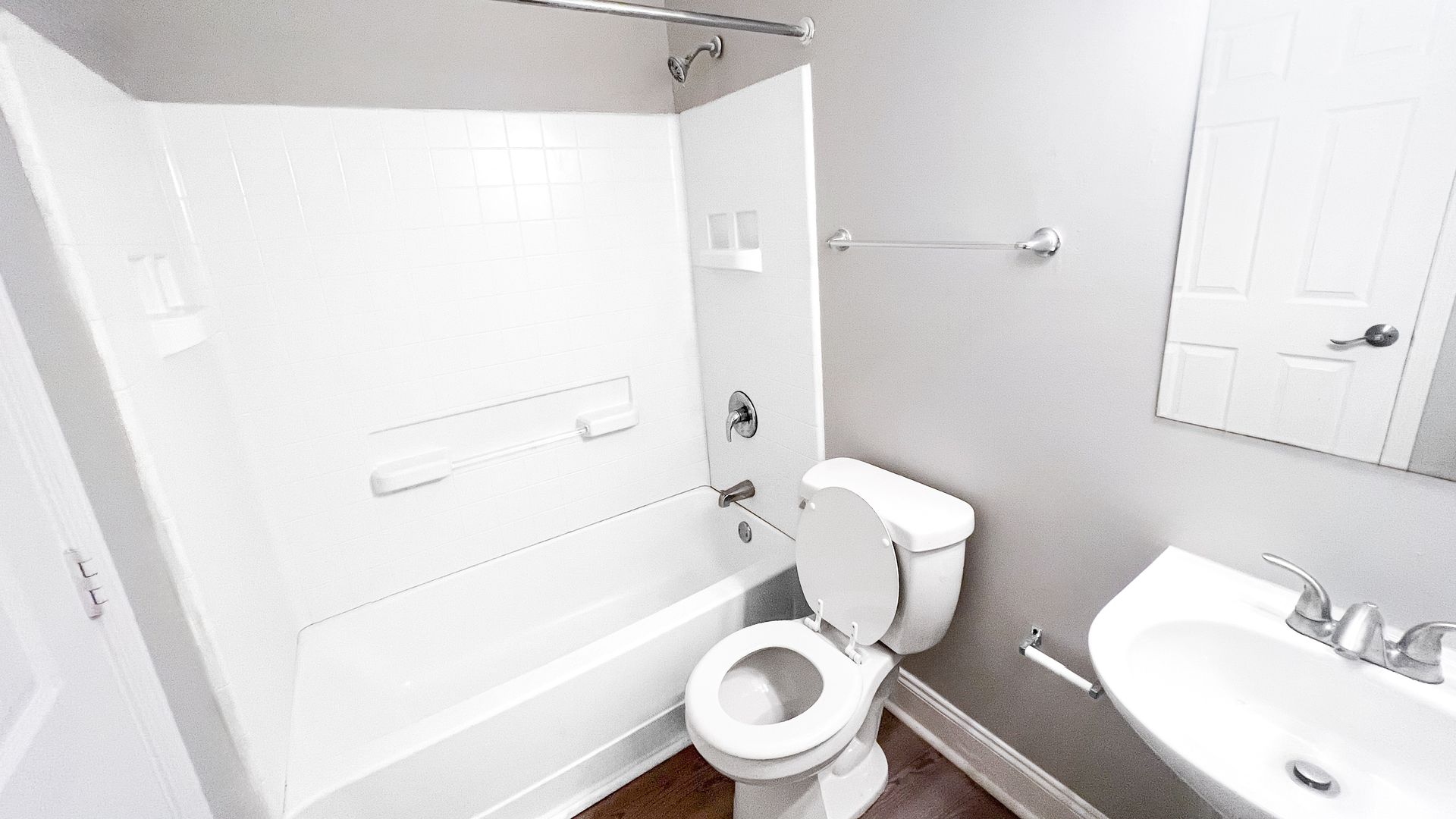 Bright bathroom with white tub, toilet, sink, and gray walls