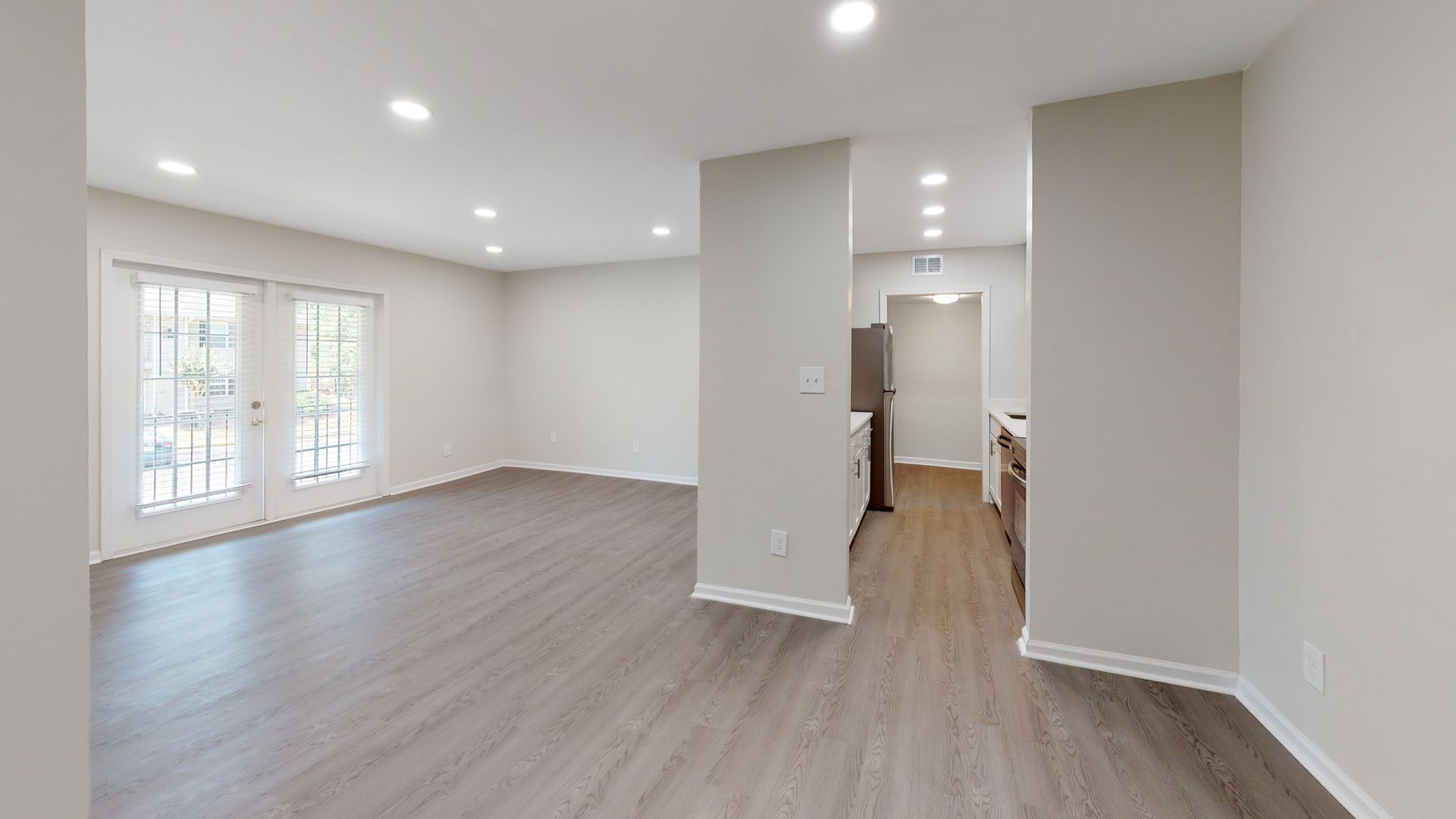 Empty beige bedroom with carpet, white trim, and a window with blinds