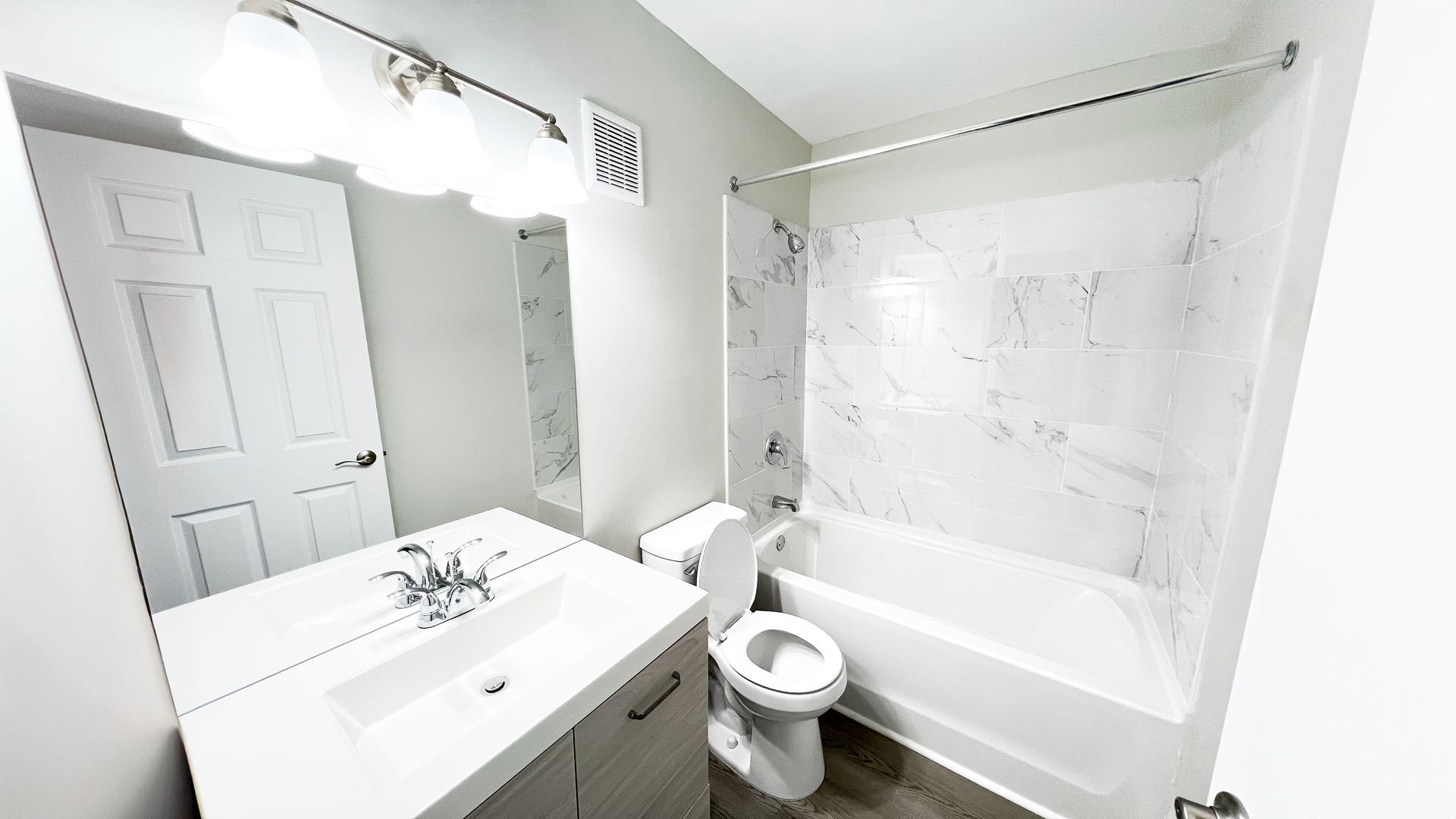 Bright white bathroom with sink, mirror, toilet, and bathtub with shower curtain.