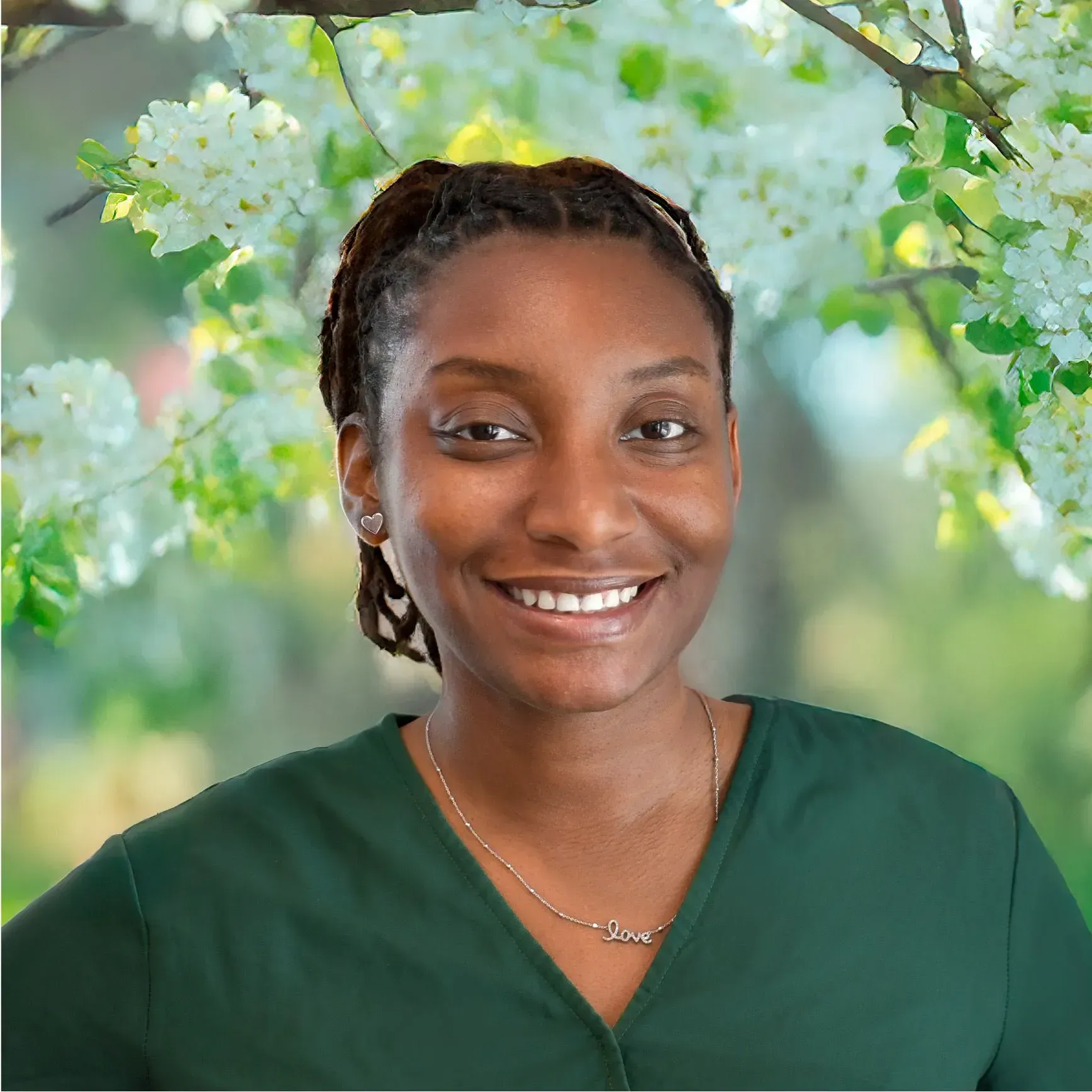 Smiling person in a green top against a soft floral backdrop
