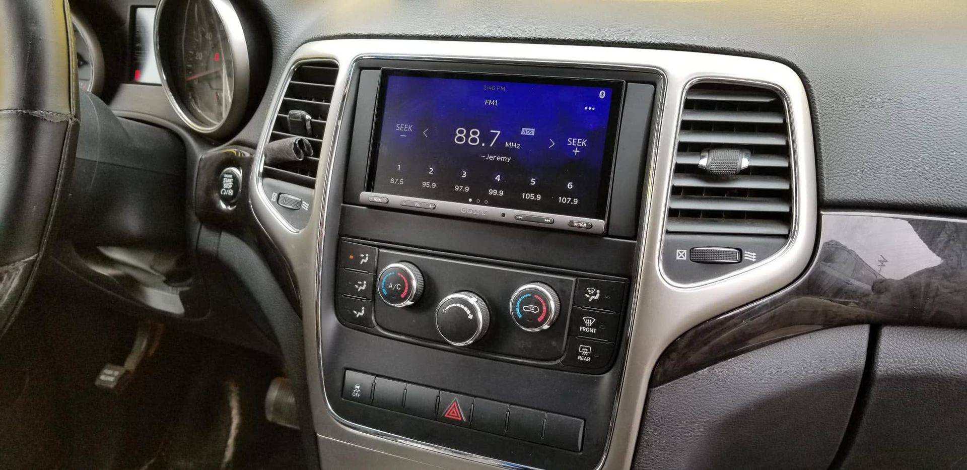 Car dashboard with center touchscreen, climate controls, and air vents in a black and silver interior