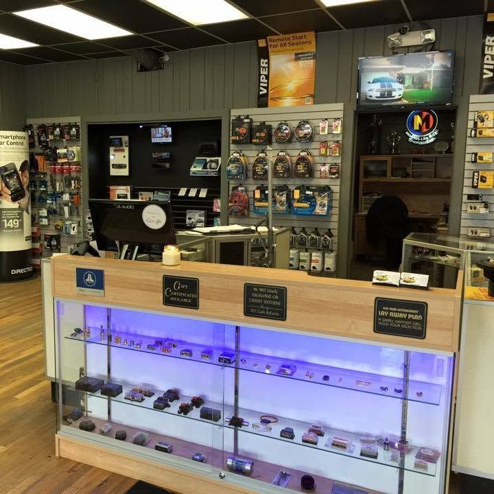 Dispensary counter with lit display cases, cannabis products, and shelves of merchandise in a shop interior