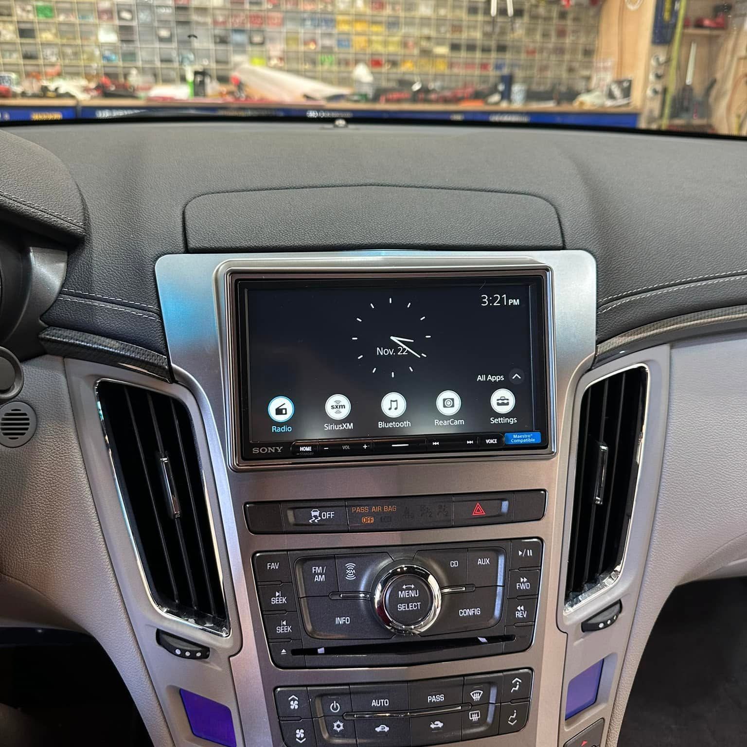Car dashboard center console with a touchscreen infotainment display and climate controls, black trim with blue accents