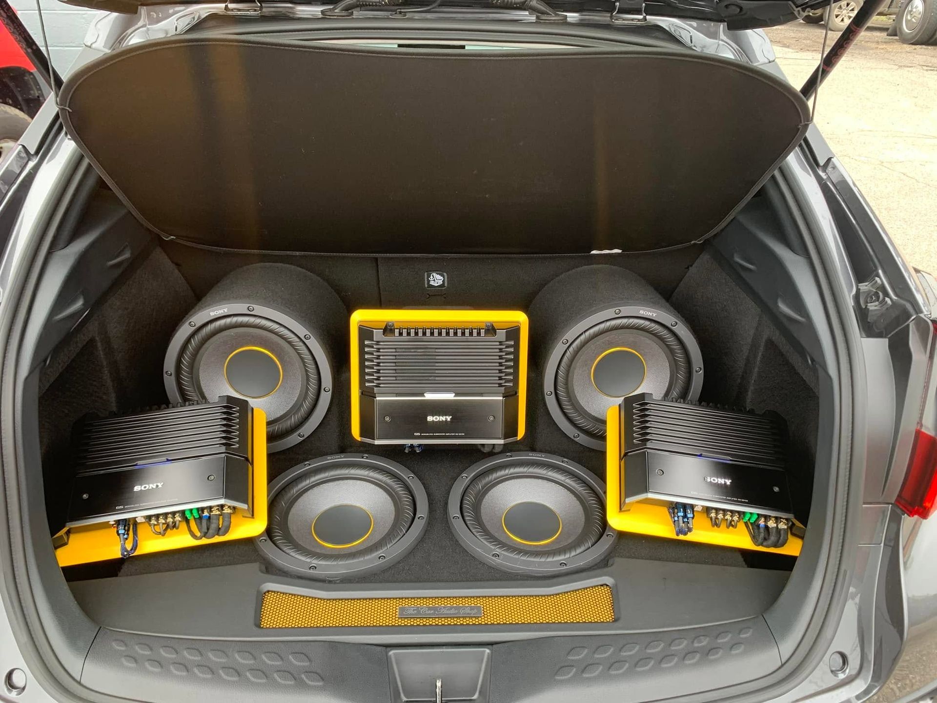 Car trunk fitted with custom yellow-and-black subwoofers and speakers, audio system installed in the cargo area