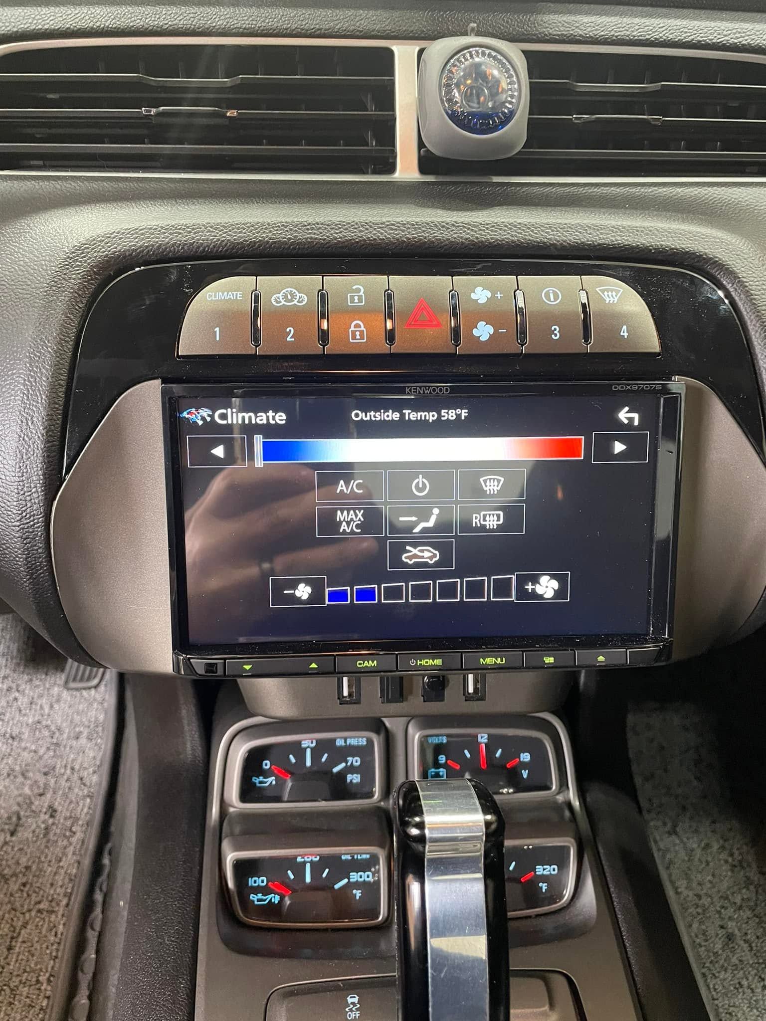 Car dashboard center console with touchscreen climate controls and vent buttons above a gear selector