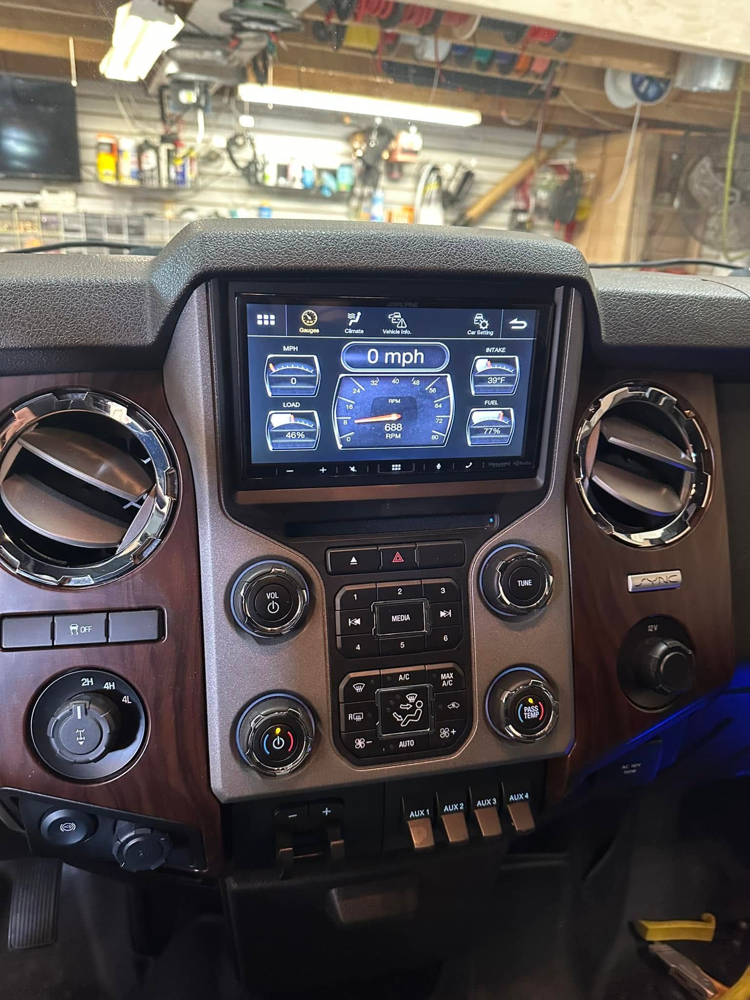 Car dashboard with touchscreen display, circular air vents, and wood trim inside a parked vehicle