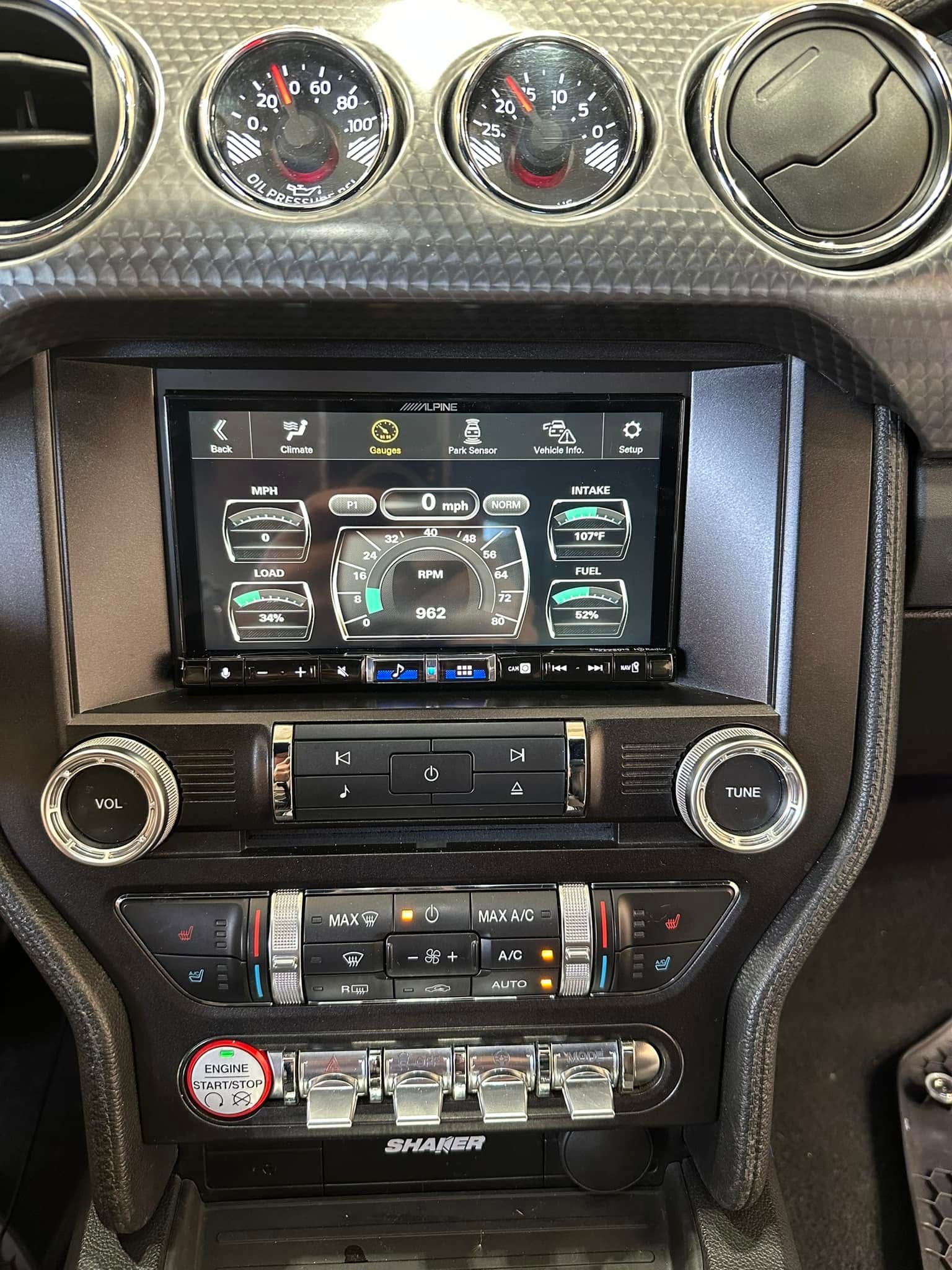 Car dashboard with touchscreen infotainment, climate controls, and round vents in black and silver trim