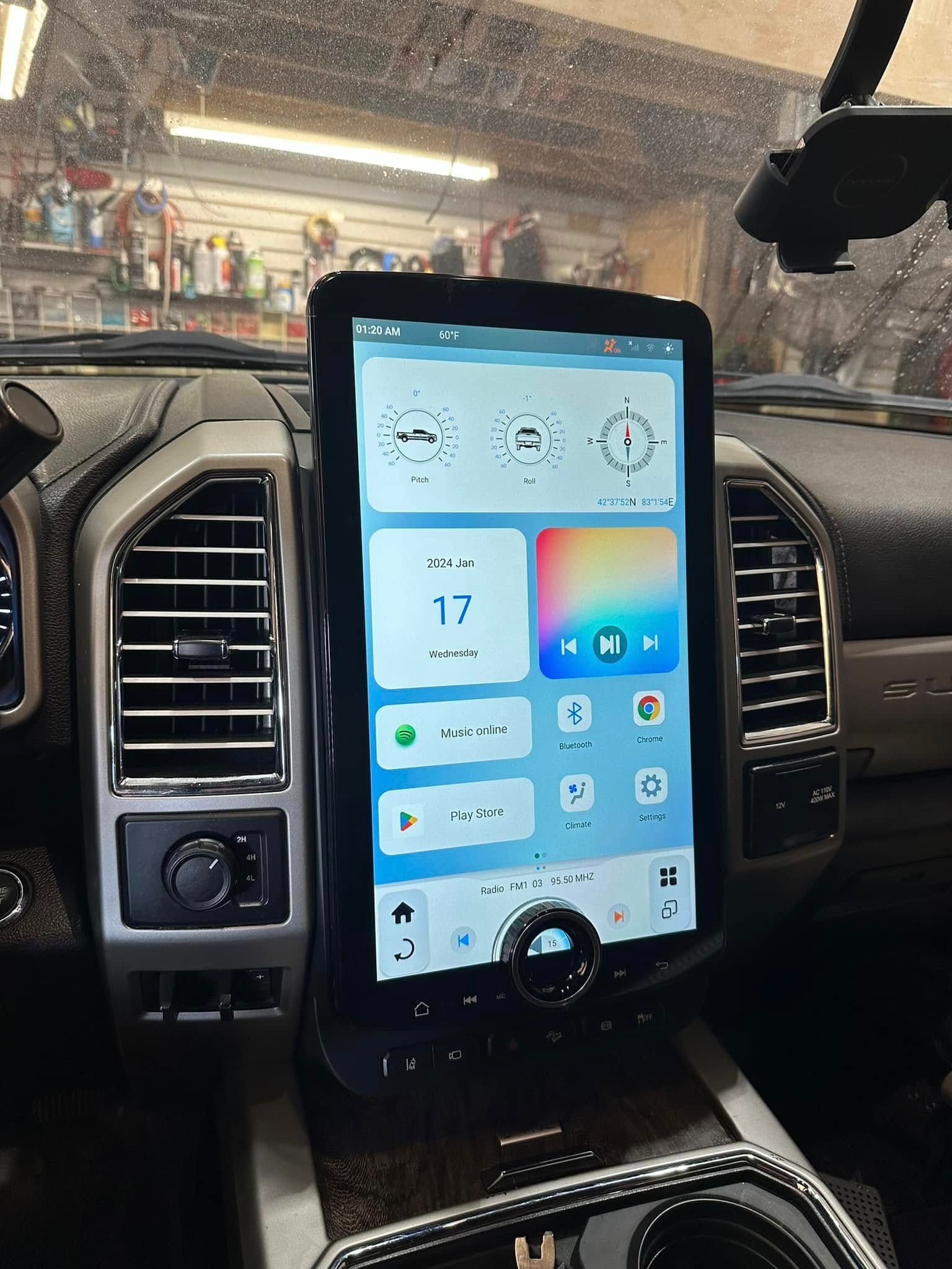 Car dashboard with a large vertical touchscreen showing a blue home screen and climate controls