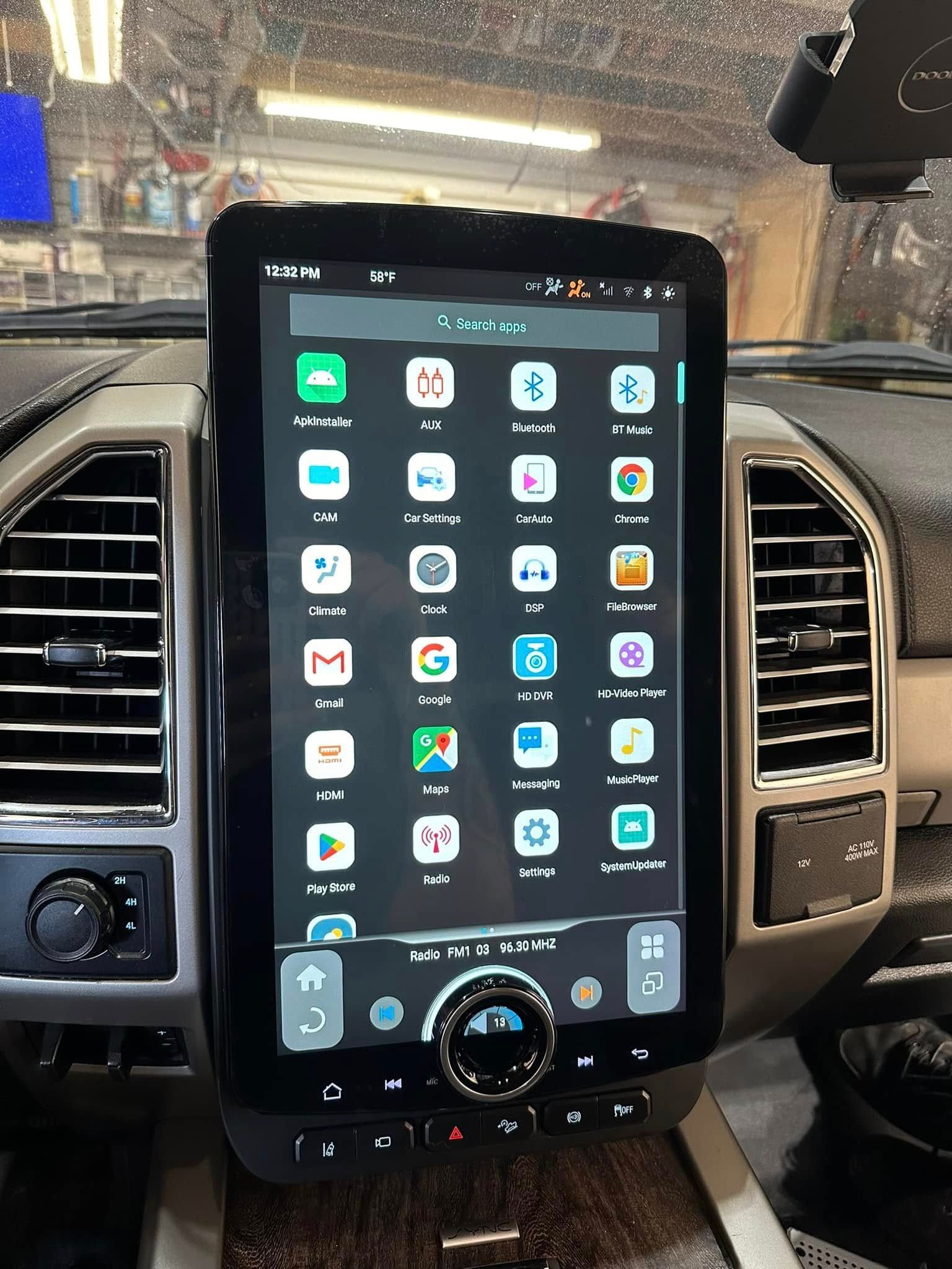Car dashboard with a large vertical touchscreen showing a grid of app icons.