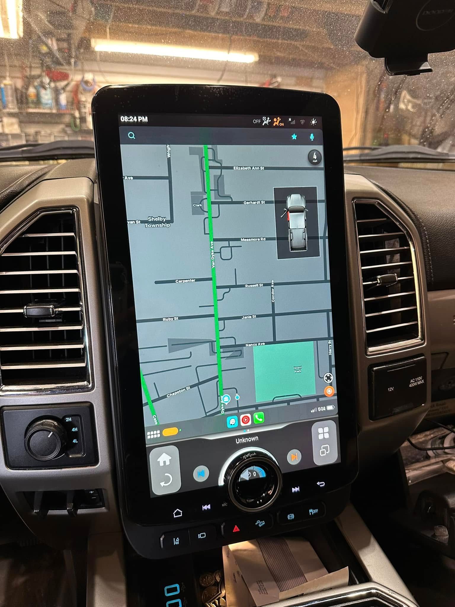 Car dashboard display showing a GPS map with a green route and traffic indicators at night
