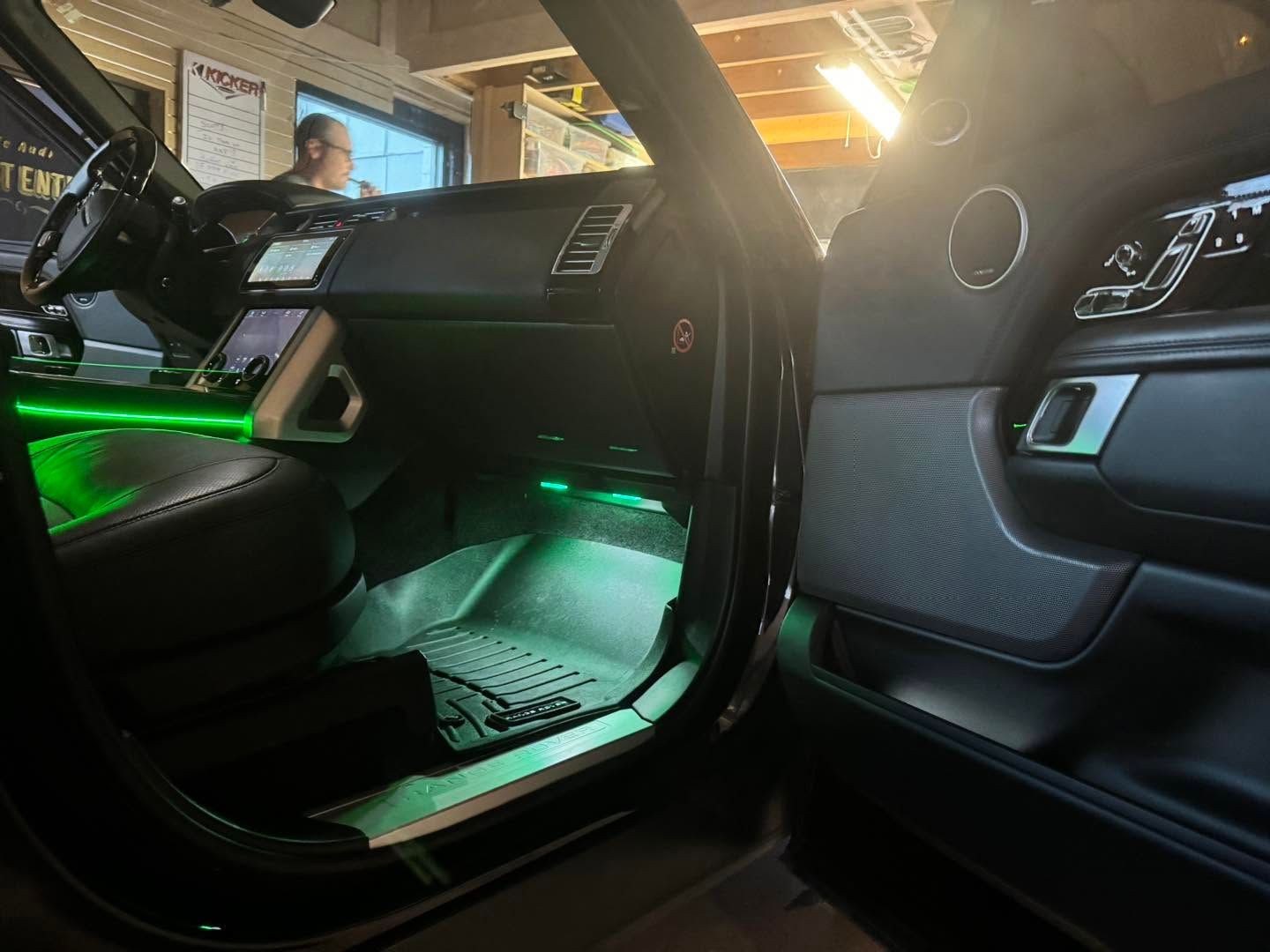 Open car door revealing a black interior with green ambient lighting.