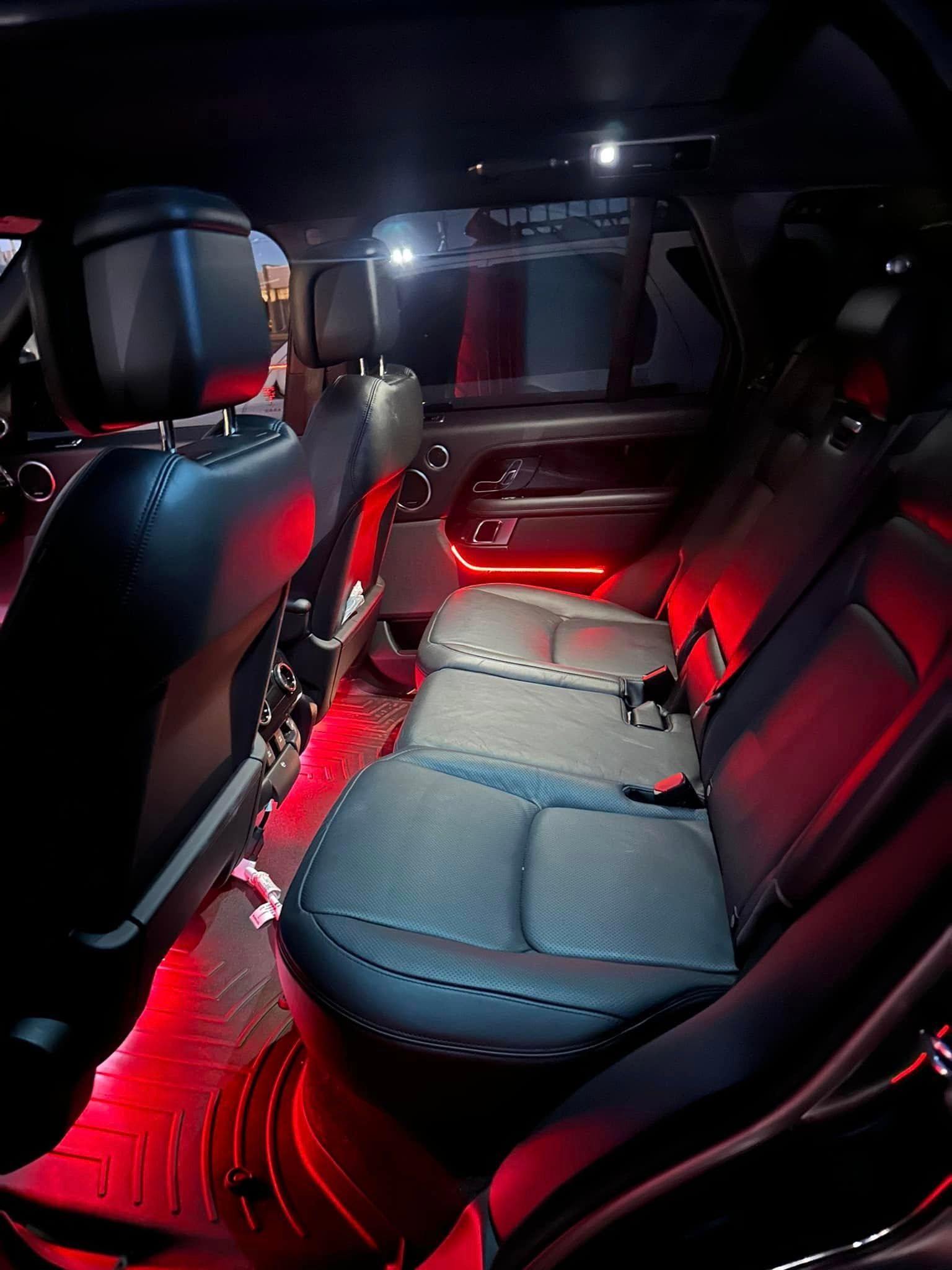 Red-lit car interior with black seats and an empty back seat bench.
