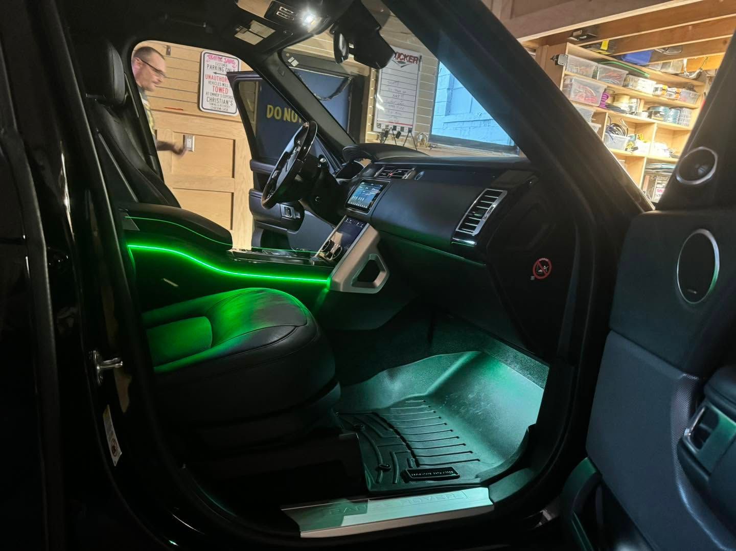 Car interior with green LED lighting, open door, and dashboard visible in a garage
