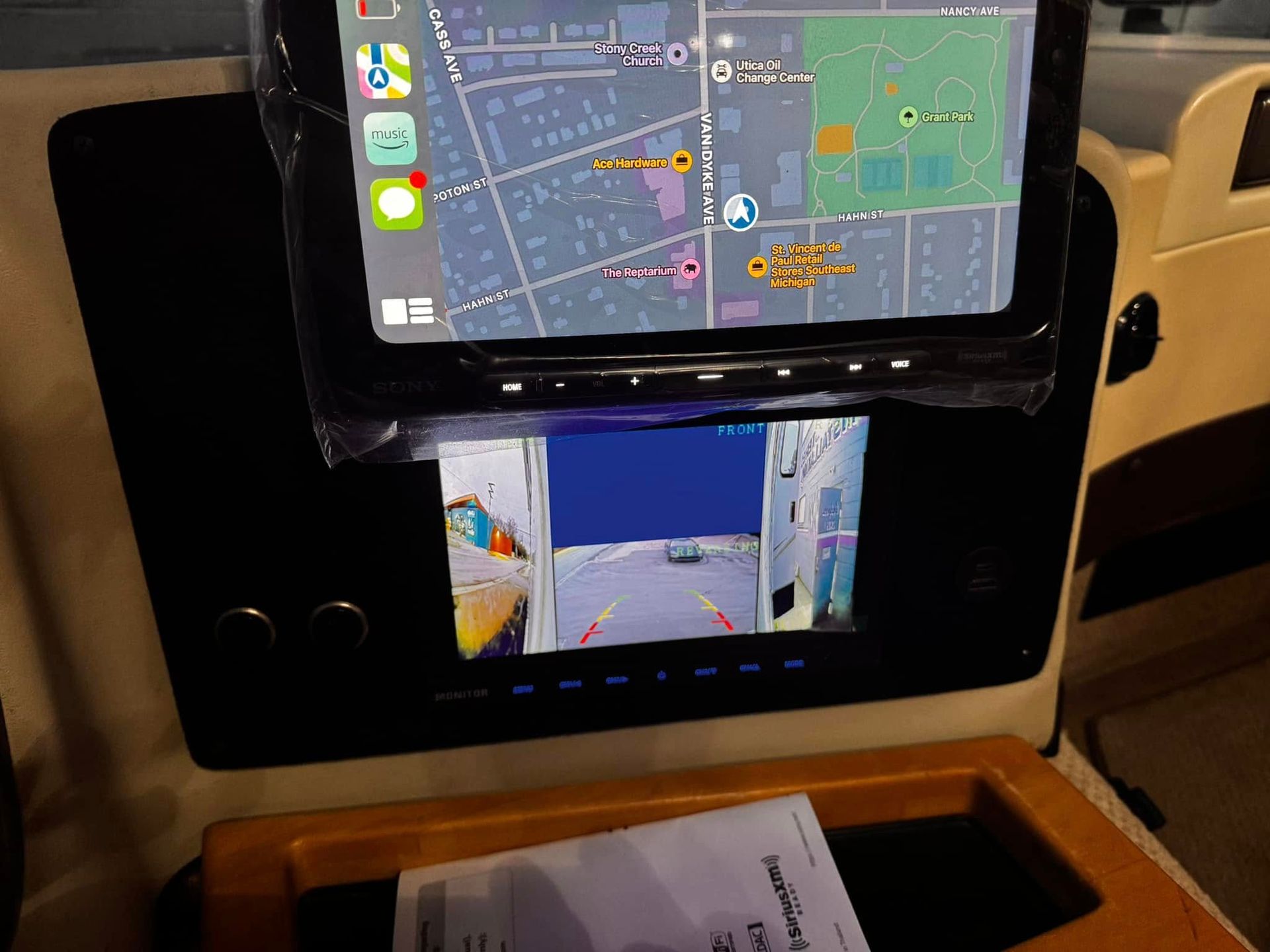 Car dashboard with two displays showing navigation map and rear-view camera feed.