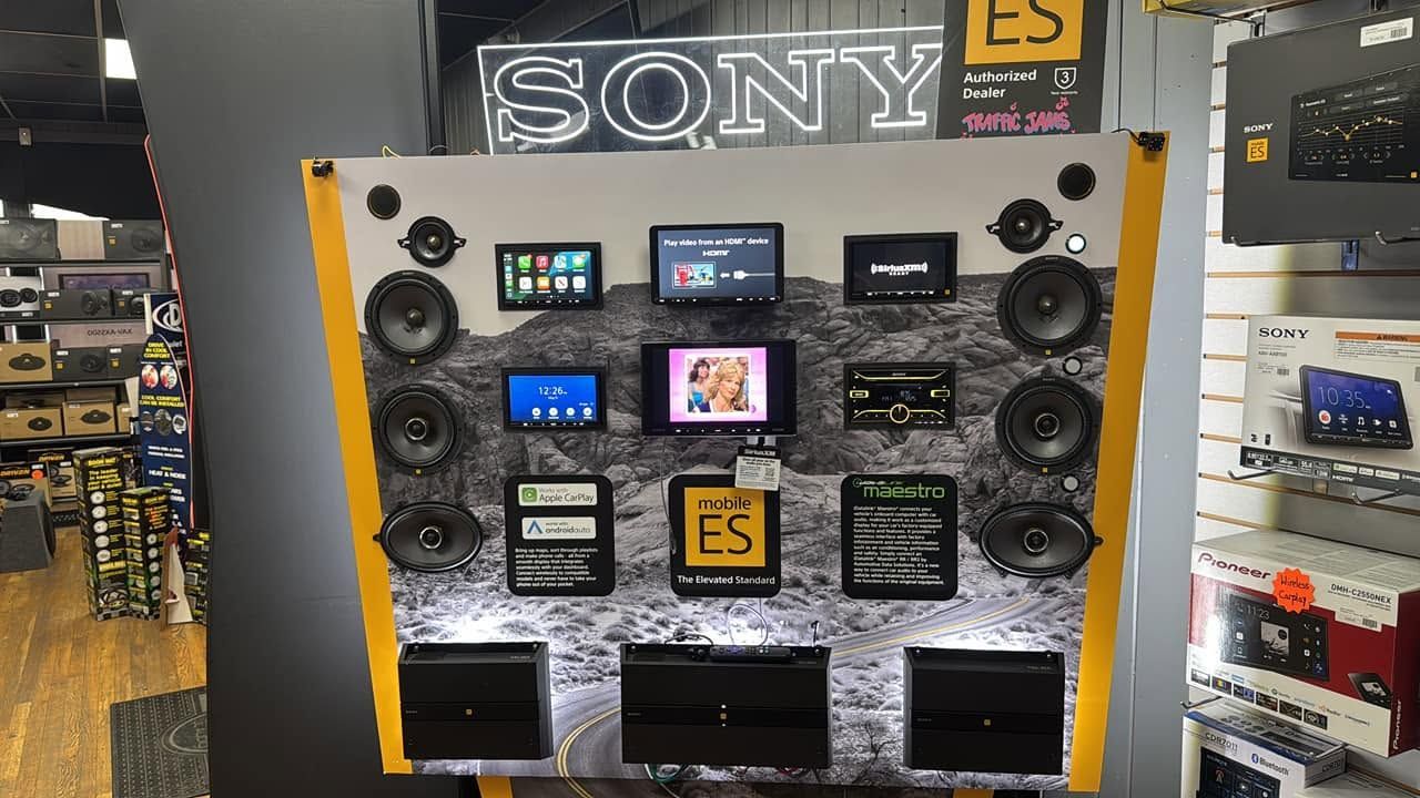Sony audio display with multiple speakers, small screens, and black subwoofers in a store.