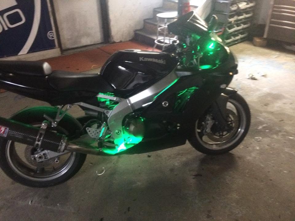 Black Kawasaki sport motorcycle with green LED lights parked in a garage.