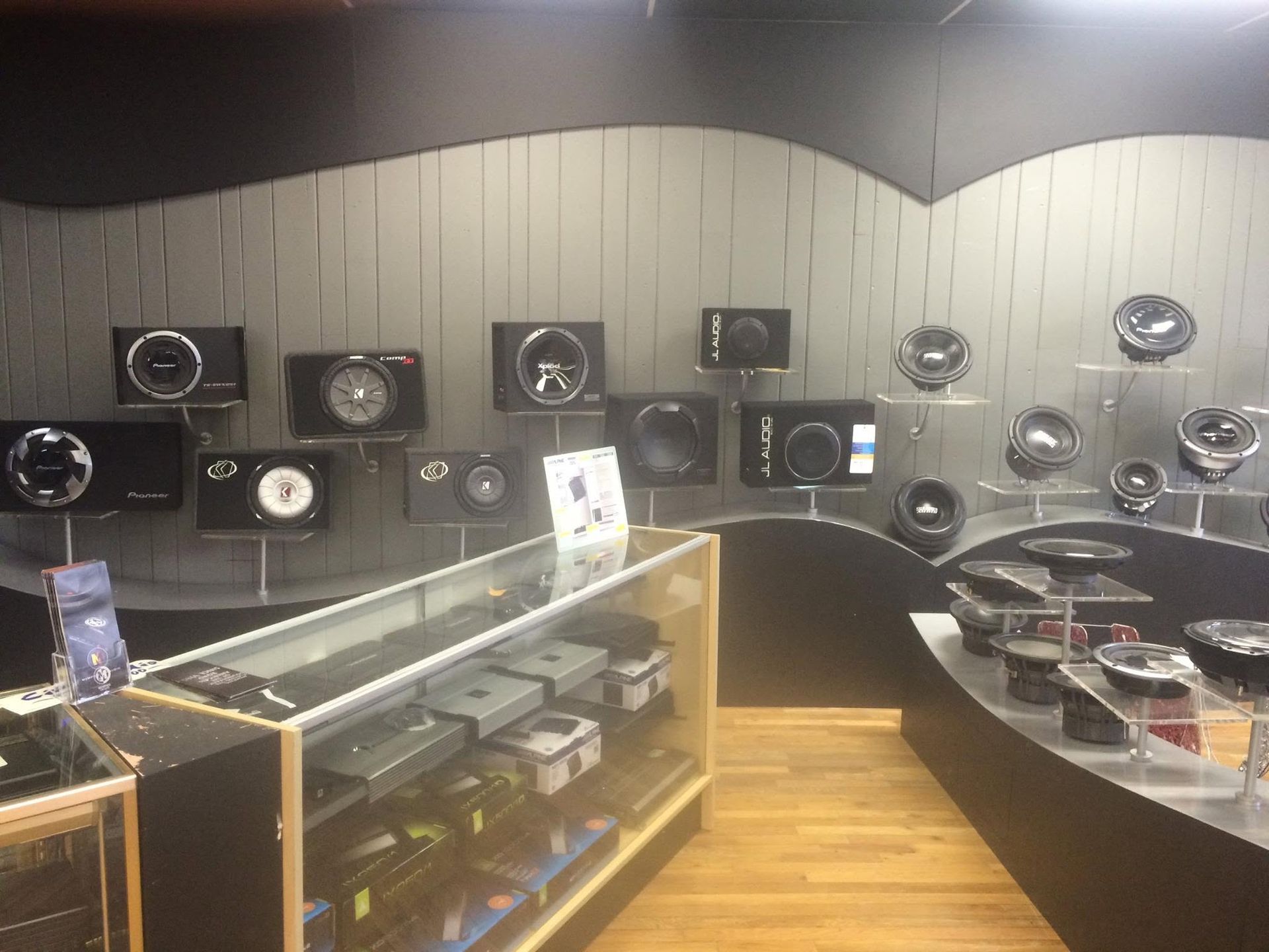 Modern speaker showroom with wall-mounted speakers and display cases on a wood floor