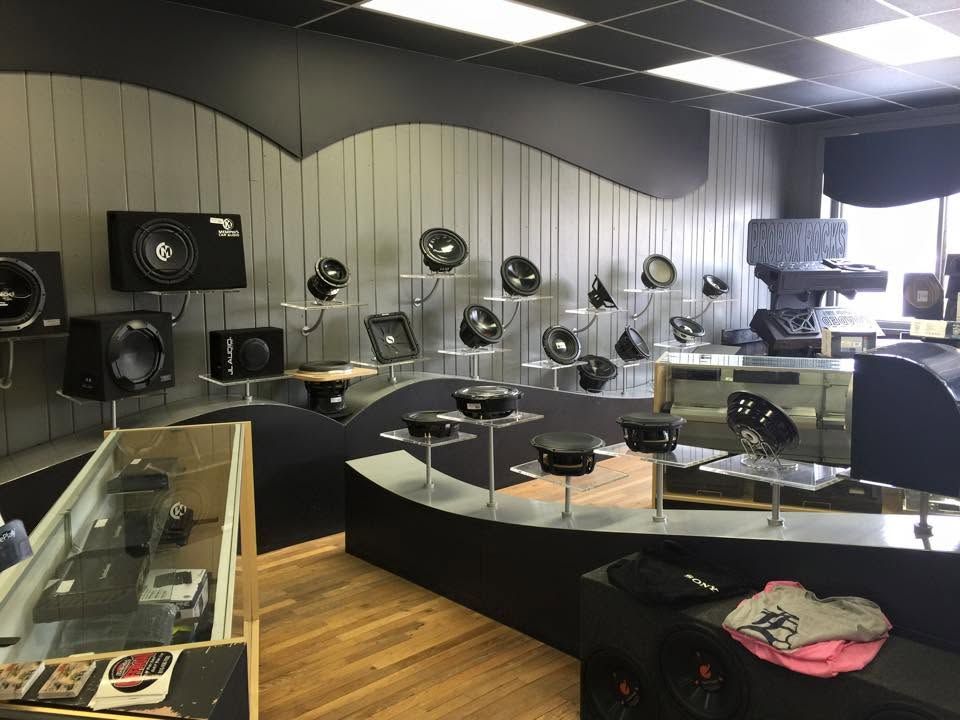 Display of car audio speakers and subwoofers in a showroom with curved black counters and wood flooring