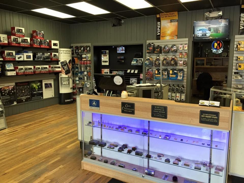 Electronics store interior with glass display cases, shelves of gadgets, and wood flooring