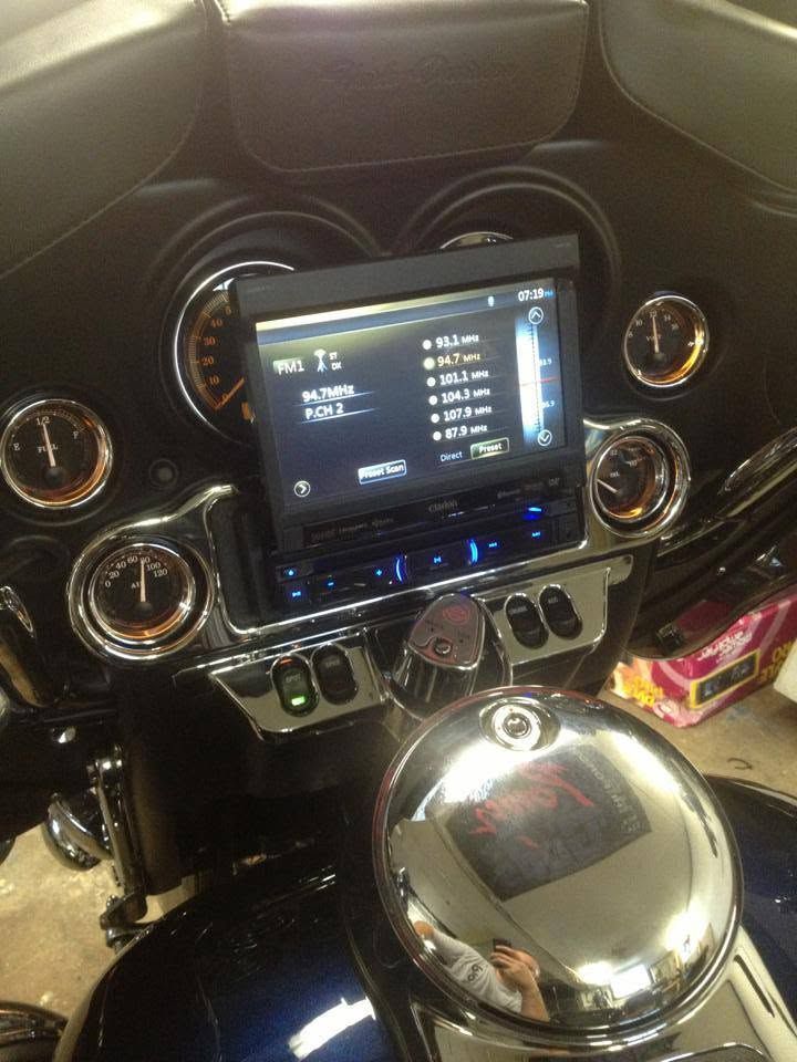 Car dashboard with touchscreen radio, circular vents, and a chrome gear shift knob.