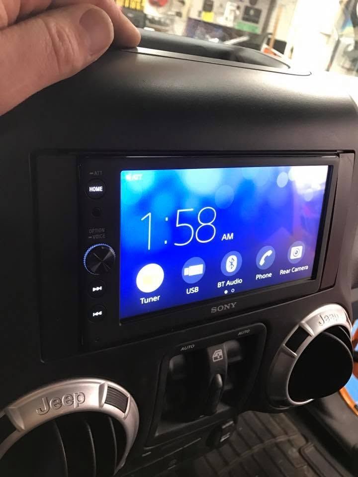 Car dashboard with Sony touchscreen stereo showing 1:58 AM and climate control knobs underneath