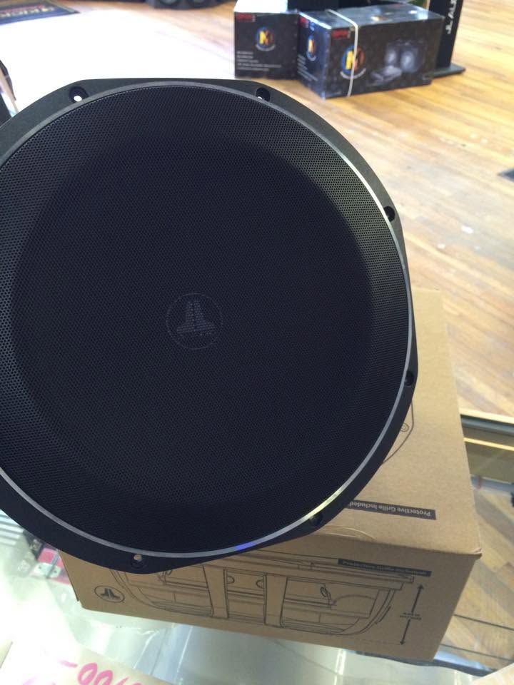 Large black speaker cone on a cardboard box in a room with hardwood floor