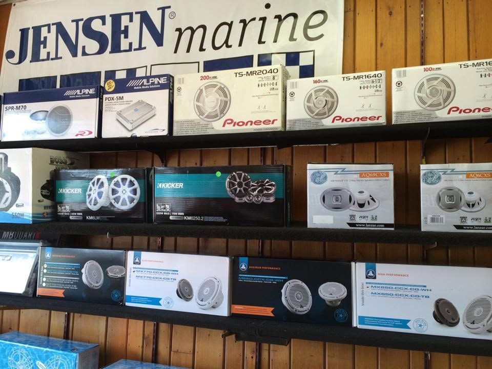 Marine audio equipment boxes displayed on shelves beneath a Jensen Marine sign