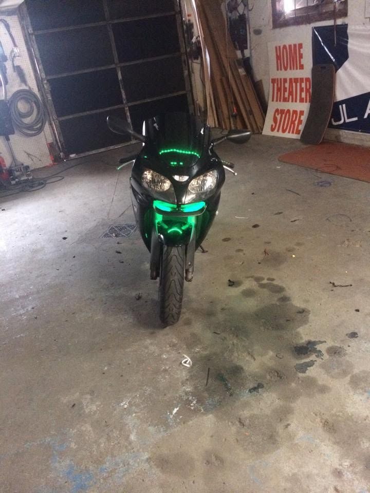 Black and green motorcycle parked indoors in a garage with signage in the background
