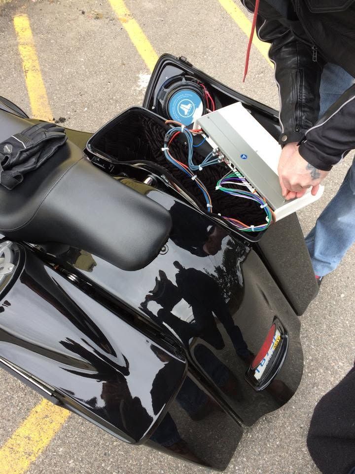 Open black motorcycle fairing with exposed wires and gauges being worked on by a person outdoors