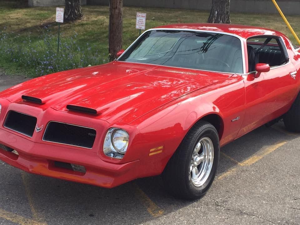 Red classic sports car parked outdoors on pavement, front-left view
