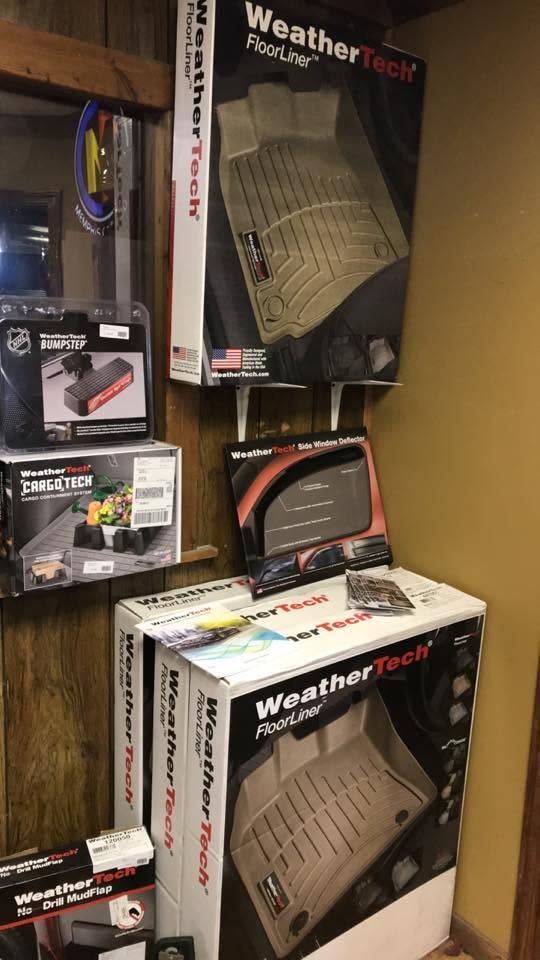 Stacked WeatherTech car floor mats and auto accessories on store shelves.