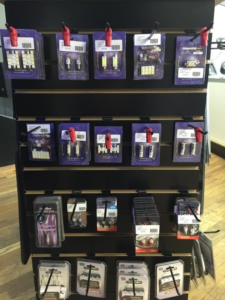 Retail display shelf with rows of packaged tools and accessories in dark shelving.