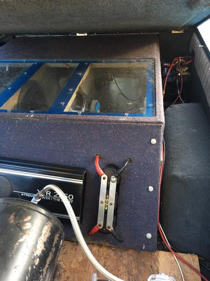 Blue speaker/subwoofer box with clear window, red wiring, and a chrome air tank in a vehicle trunk
