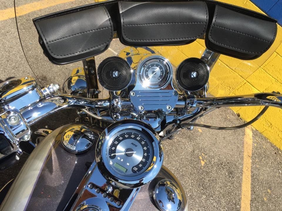 Motorcycle handlebars and chrome instrument cluster with black leather windshield bag and saddlebag panels