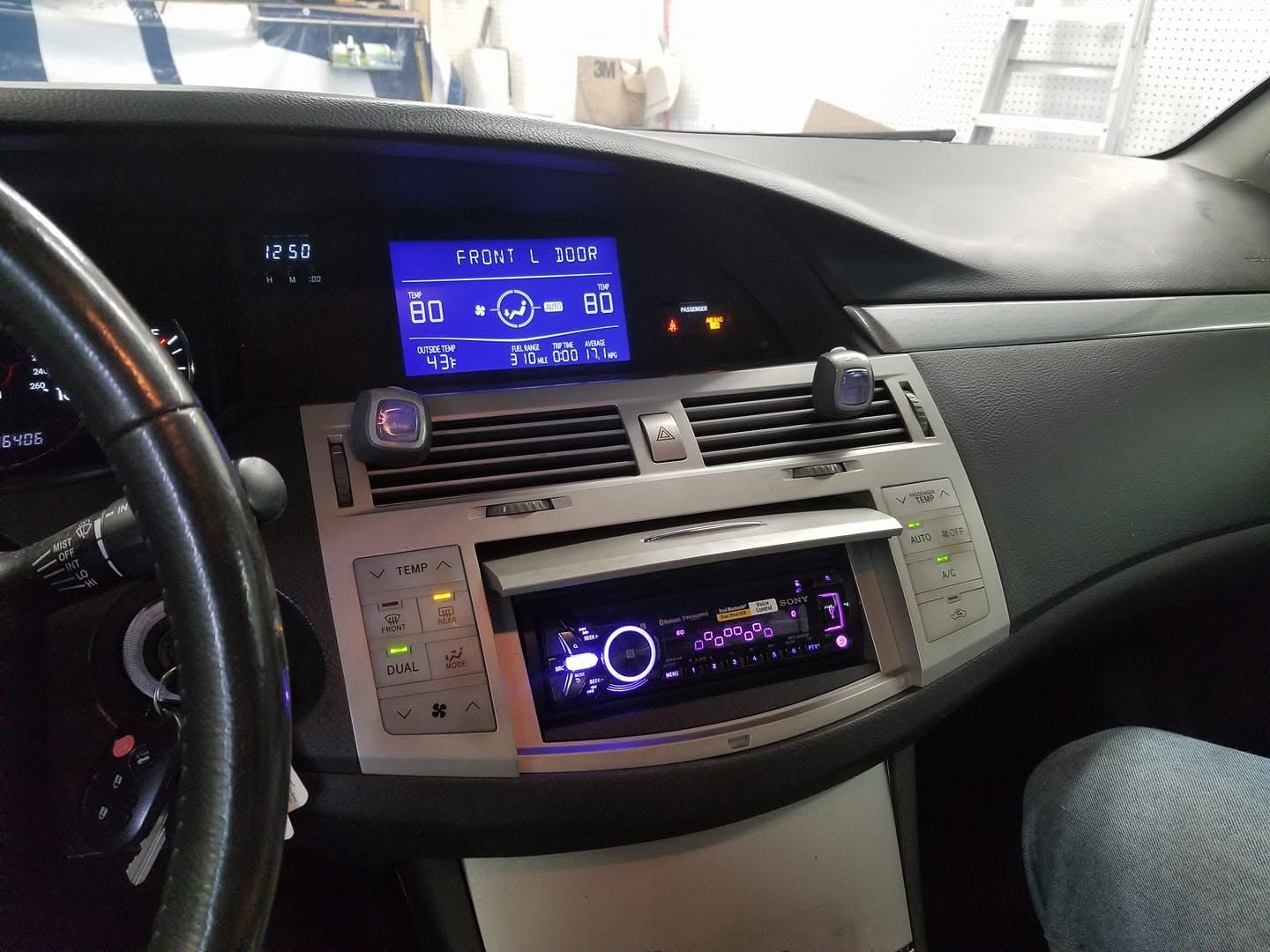 Car dashboard with blue digital display, center stereo controls, and passenger seat visible