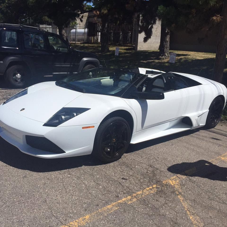 White Lamborghini convertible parked on a street in daylight