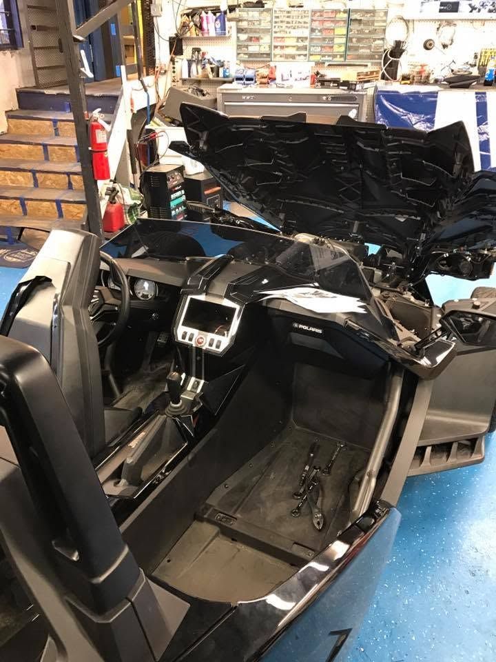 Damaged black car interior with broken dashboard and open door in a workshop