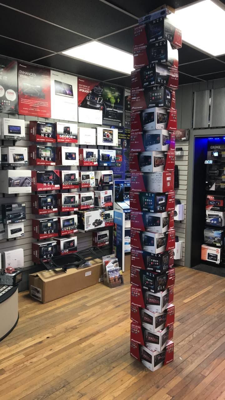 Store interior with shelves of boxed products and a tall stack of boxes in the center aisle.