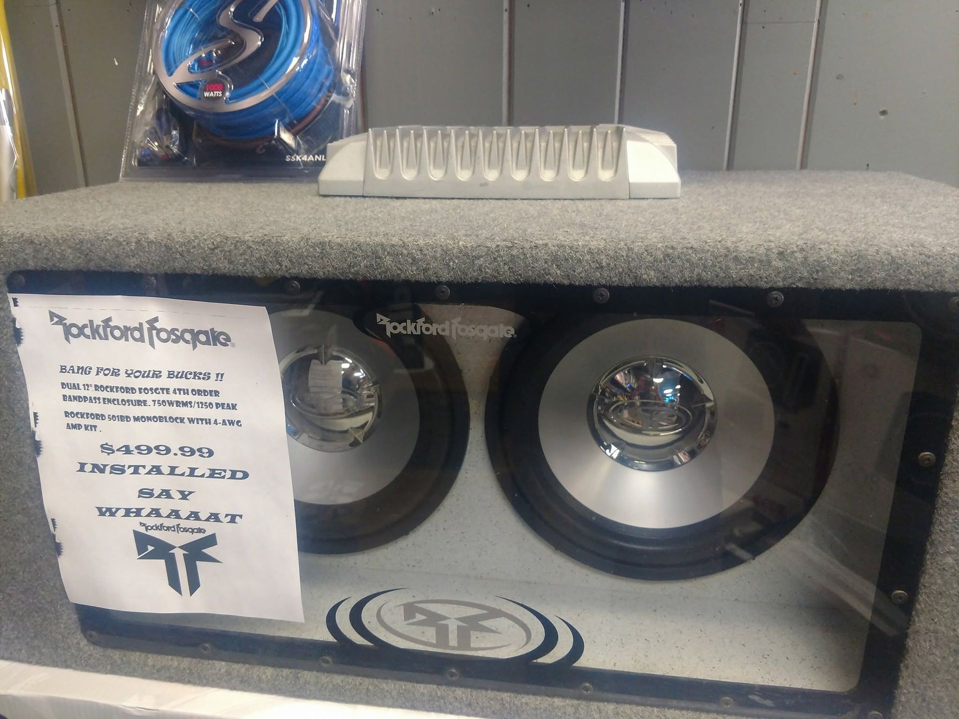 Car stereo subwoofer box with two speakers and a small sign on the left side