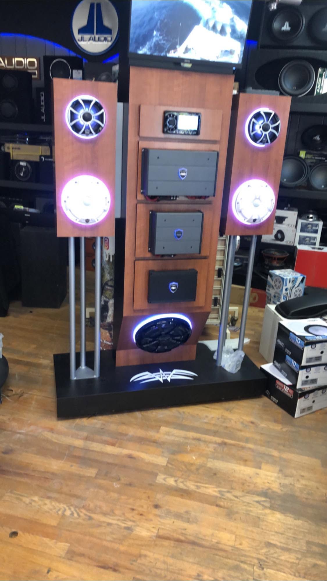 Tall speaker/display system with glowing pink lights and multiple speakers in a store or showroom.