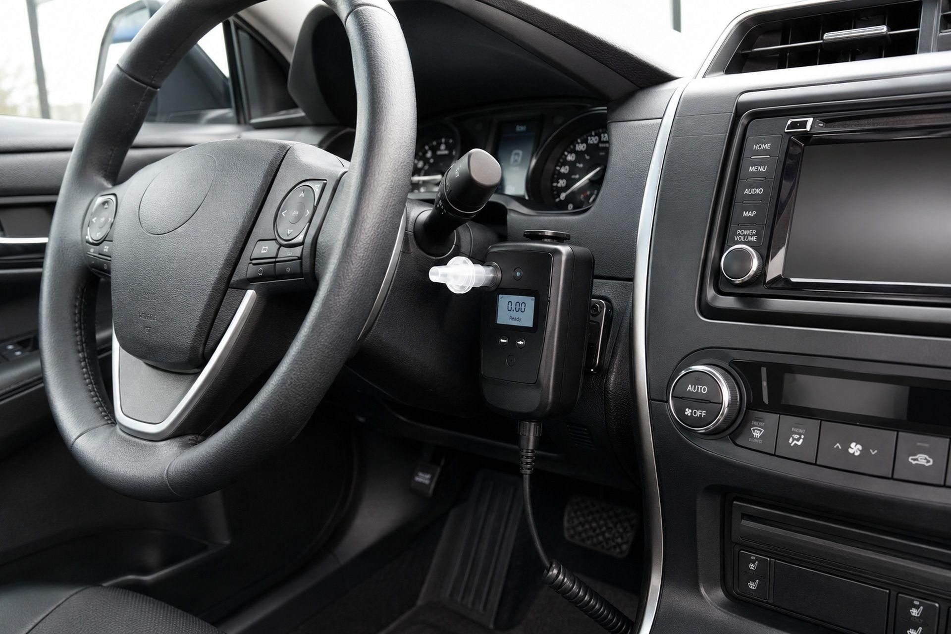 Car dashboard and steering wheel with a key in the ignition and center console controls