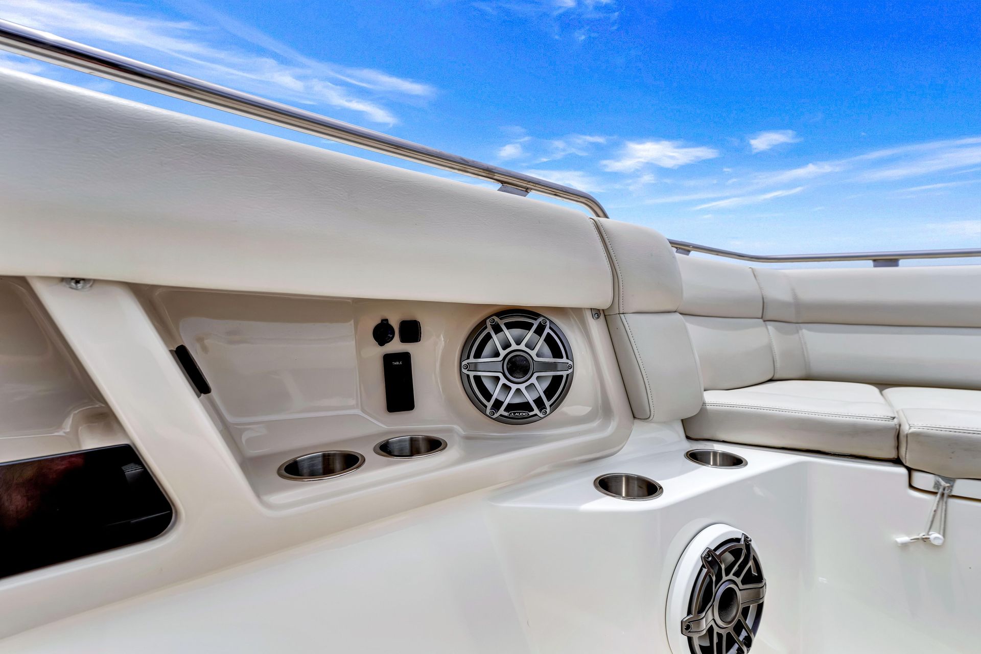 White boat cockpit with cushioned seating, speakers, and a blue sky overhead