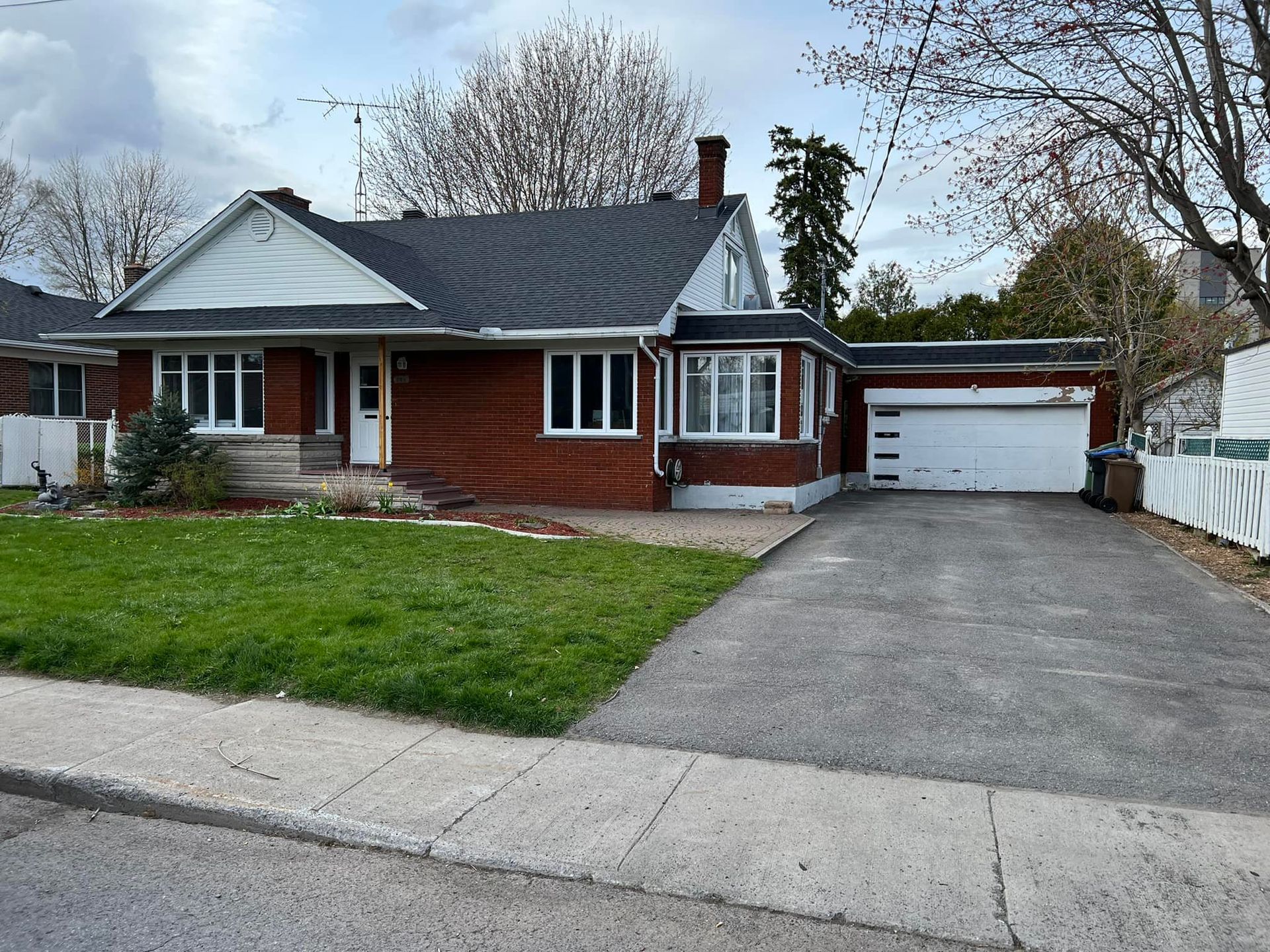 Single-story brick house with attached garage and long driveway in a suburban neighborhood