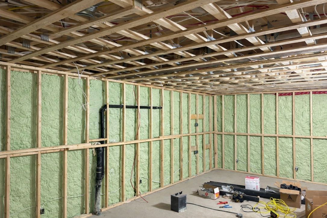 Worker nailing plywood sheathing on a steep roof under construction