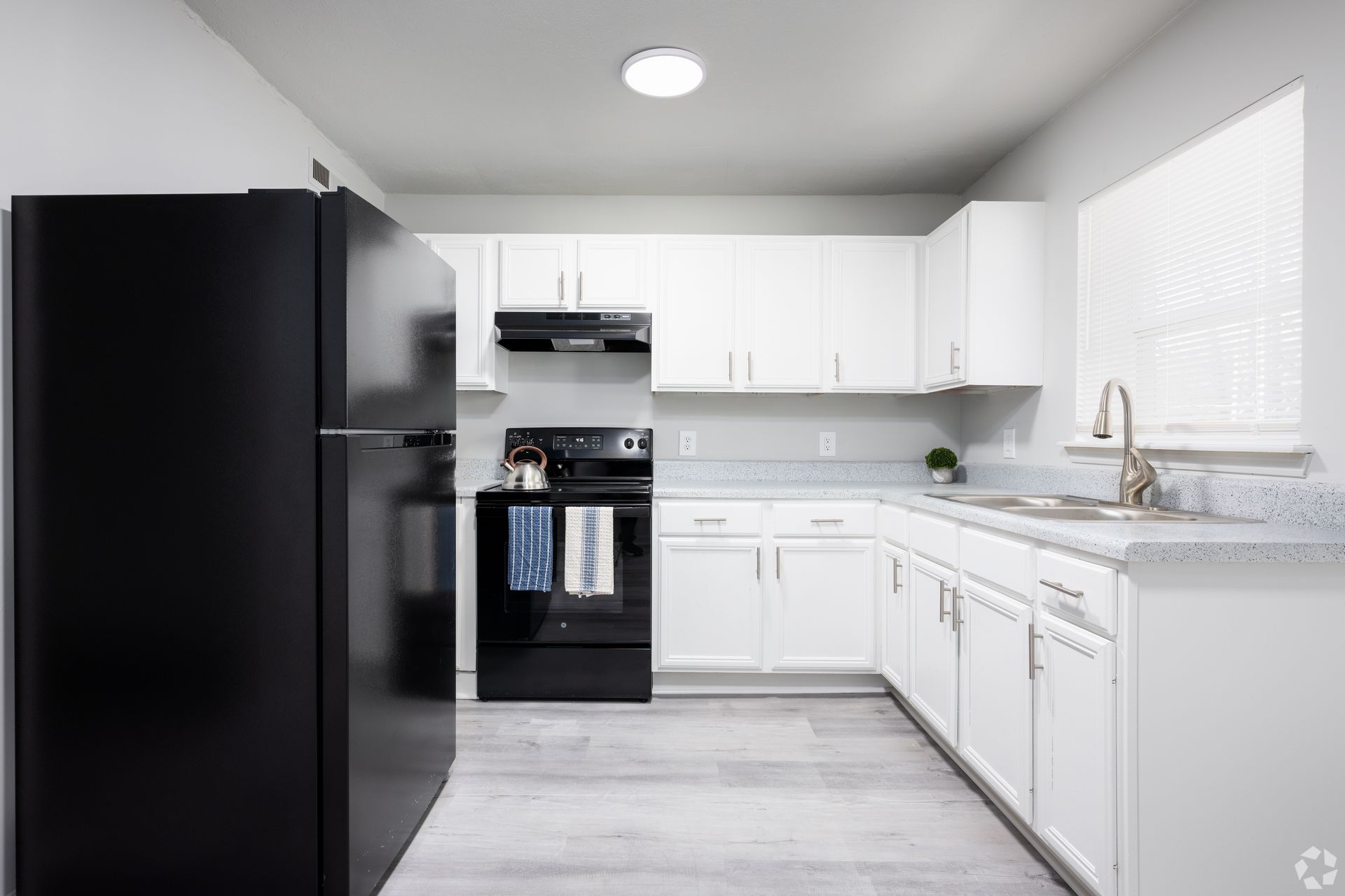 A kitchen with white cabinets , black appliances , and a black refrigerator.