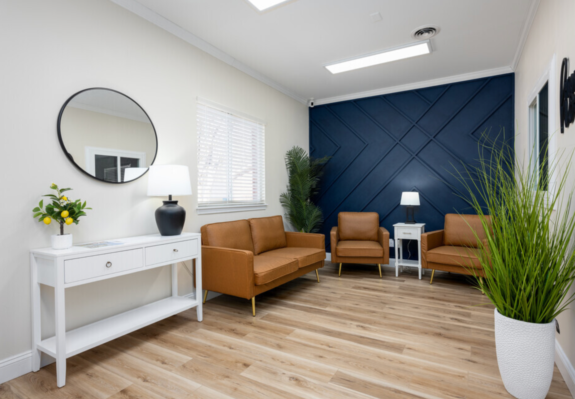 A living room with a couch , chairs , and a mirror.